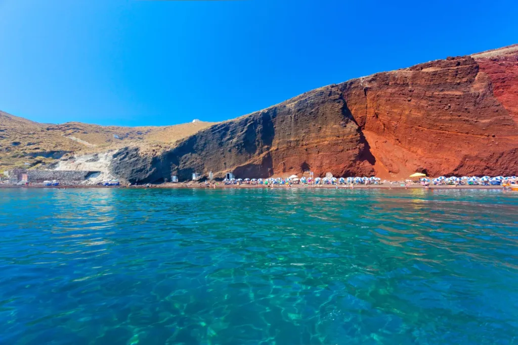 Red Beach z ciemnymi wulkanicznymi klifami i czerwonym piaskiem